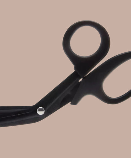 Liebe Seele Veiligheidsschaar – Zwart Hands demonstrating black angled scissors beside a black cuff with red lining.
