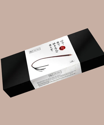 Liebe Seele Bull Whip – Wijnrood Red and black braided bull whip with black split tip, arranged vertically in a curve.