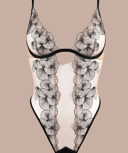 Atelier Amour – Menu Plaisir Body Zwart Model wearing black Menu Plaisir bodysuit with sheer floral embroidery and open centre front.