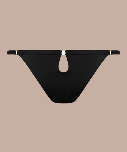 Maison Close – Fatale Slip Zwart – Lingerie & Bikini / Badkleding Model wearing black Fatale briefs and matching crossed-strap bra, front view with one arm raised.