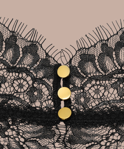 Maison Close/Scandale โ Inspiration Divine Open Back Lace Thong Body Black Inspiration Divine black Open Back Lace Thong Body with sheer floral lace and a gold-tone cross at the collar, front view on model.