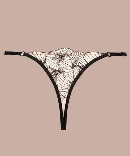 Atelier Amour – Menu Plaisir String Zwart Model wearing black Menu Plaisir floral thong and matching underwire bra, one hand beside her head.