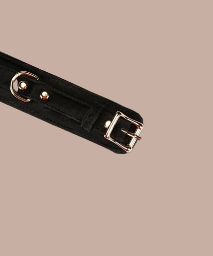Liebe Seele Boudoir Amor Vegan Enkelboeien – Zwart Pair of Liebe Seele Boudoir Amor black ankle cuffs connected by a gold-tone chain.