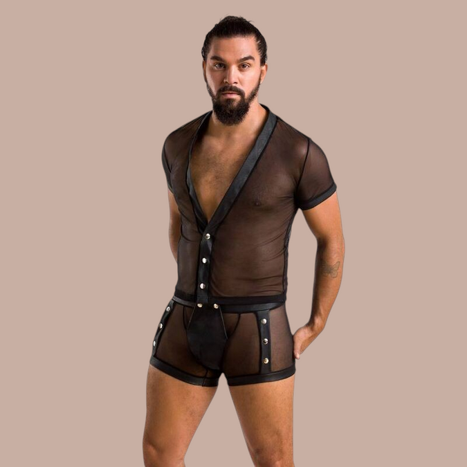 Man met baard draagt Pleasurements Passion 052 Michael set, een zwart doorschijnend ondergoedsetje met drukknopen.