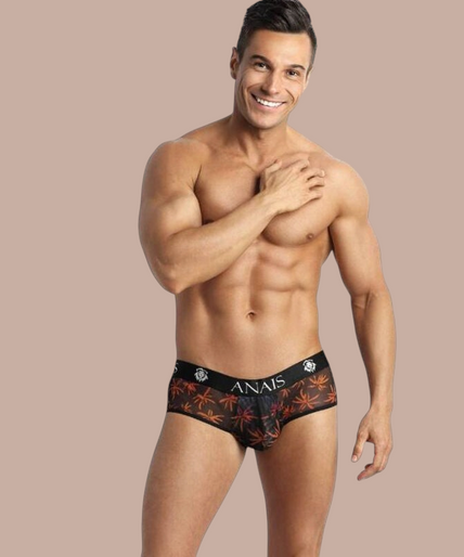 Anais Men – Chill Jock Bikini | Premium Men’s Underwear Pleasurements Anais Men Chill Jock Bikini met palmboomprint en zwarte tailleband gedragen door een lachend model