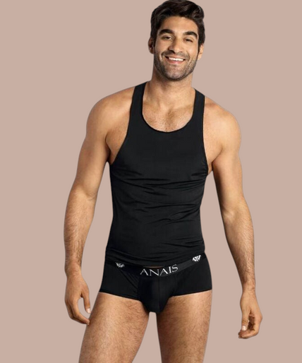 Anais Men – Petrol Top S Pleasurements Anais Men Petrol top in zwart gedragen door een glimlachend model als onderdeel van premium ondermode.