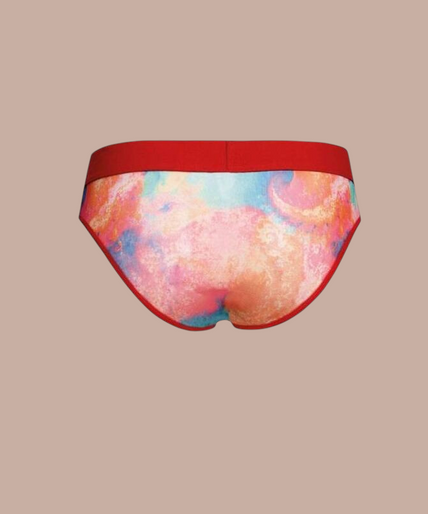 Anais Men – Falcon Slip S Pleasurements Anais Men Falcon slip met kleurrijk tie-dye patroon en rode tailleband gedragen door een model