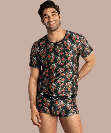 Anais Men – Power T-Shirt S Pleasurements Anais Men Power T-shirt met zwart, rood en wit schedel- en rozenpatroon gedragen door een lachend model