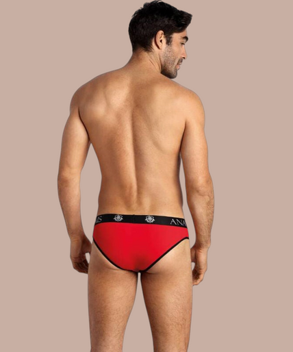 Anais Men – Soul Slip S Pleasurements Anais Men Soul Slip in rood met zwarte tailleband gedragen door een glimlachend model