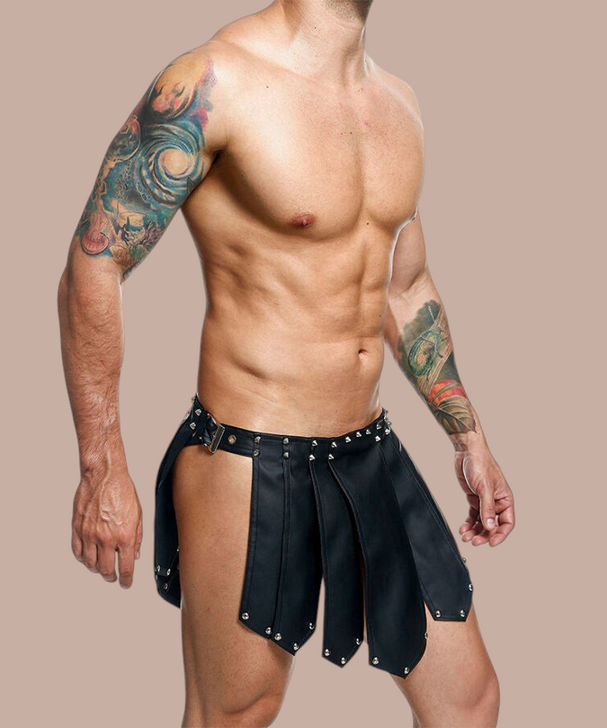 Pleasurements Mob Dngeon zwarte leren rok met metalen studs gedragen door een man met tatoeages