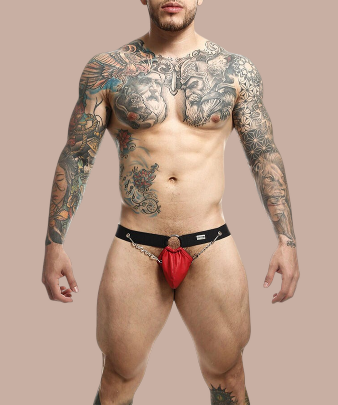 Pleasurements Mob Dngeon rode jockstrap van leer met metalen kettingen gedragen door een getatoeëerde man