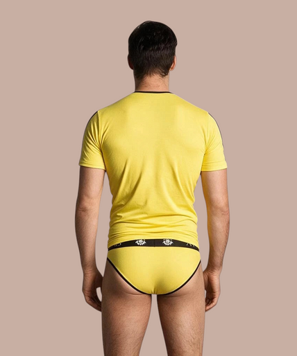 Anais Men – Tokio T-Shirt | Premium Men’s Underwear Pleasurements Anais Men Tokio T-shirt in geel met zwarte accenten gedragen door een glimlachend model
