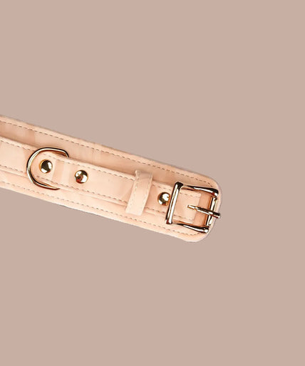 Angled view of Liebe Seele Boudoir Amor blush pink wrist cuffs showing buckles, lining and connector chain.
