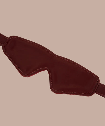 Dark red blindfold with stitched edges and adjustable buckle strap, front view.