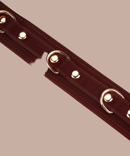 Dark red Liebe Seele collar with rose-gold-tone chain leash and matching loop handle.