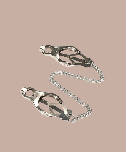 Pair of silver-tone clover nipple clamps joined by a chain, curved arrangement.