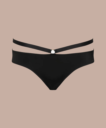Model wearing black Fatale tanga with a raised waist strap and matching crossed-strap bra, side view.