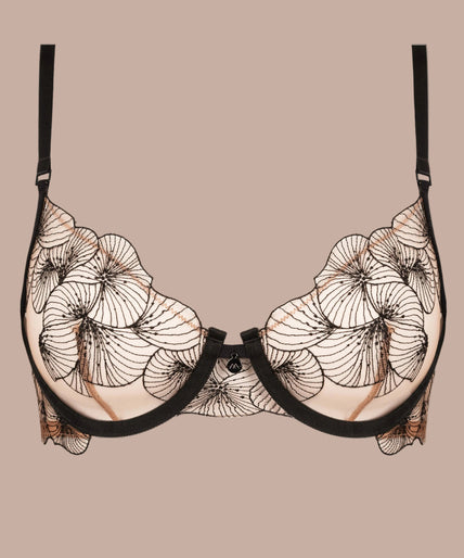 Model wearing black Menu Plaisir embroidered balconette bra and matching thong, one hand beside her head.