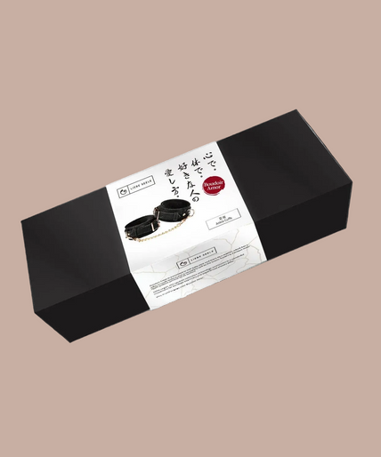 Pair of Liebe Seele Boudoir Amor black ankle cuffs connected by a gold-tone chain.