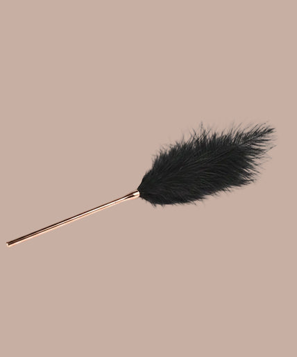 Black feather tickler with slender rose-gold-tone handle, shown vertically.