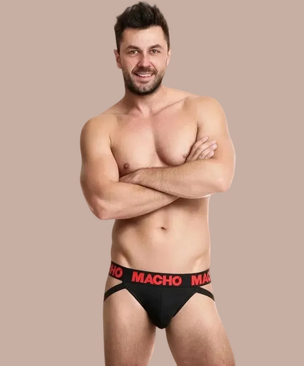 Pleasurements Macho MX26X2 jockstrap in zwart met rode tailleband gedragen door een model met gekruiste armen.