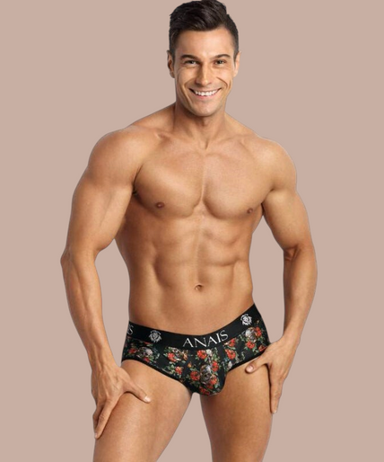 Pleasurements Anais Men Power Jock Bikini met bloemenprint en zwarte tailleband gedragen door een gespierd model