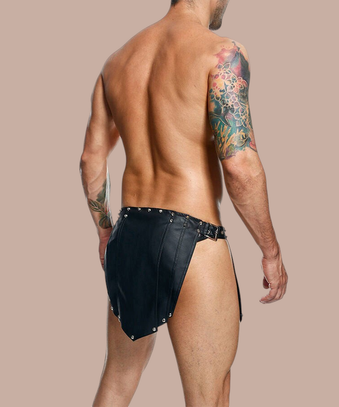 Pleasurements Mob Dngeon zwarte leren rok met metalen studs gedragen door een man met tatoeages op de rug