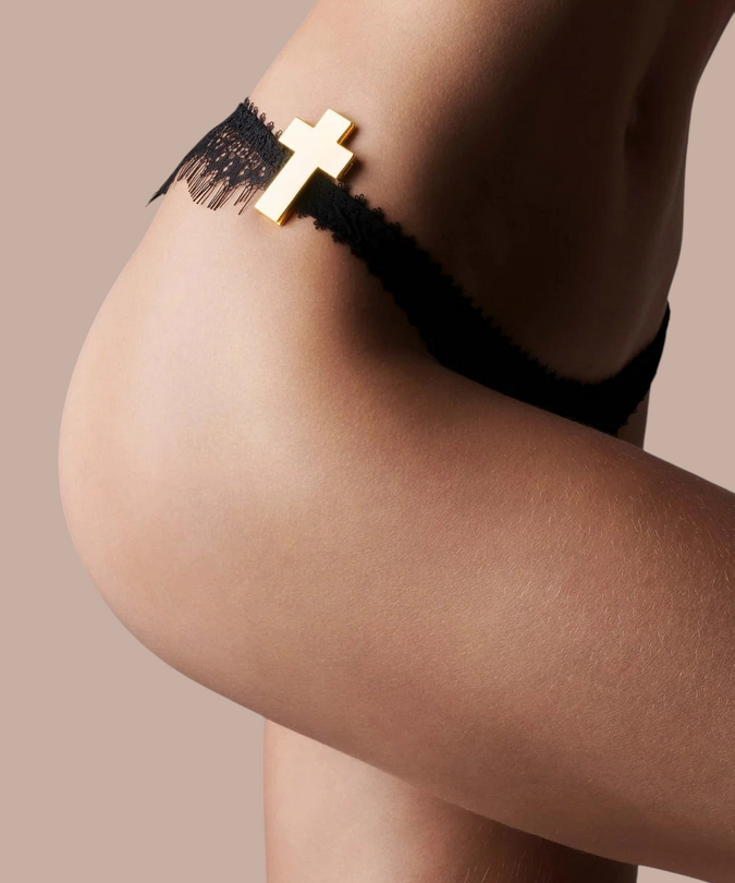 Pleasurements Maison Close Inspiration Divine gouden kruis sieraad bevestigd aan een zwarte kanten string