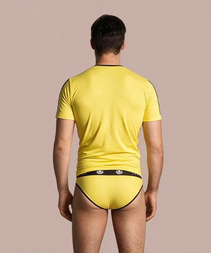 Pleasurements Anais Men Tokio T-shirt in geel met zwarte accenten gedragen door een glimlachend model